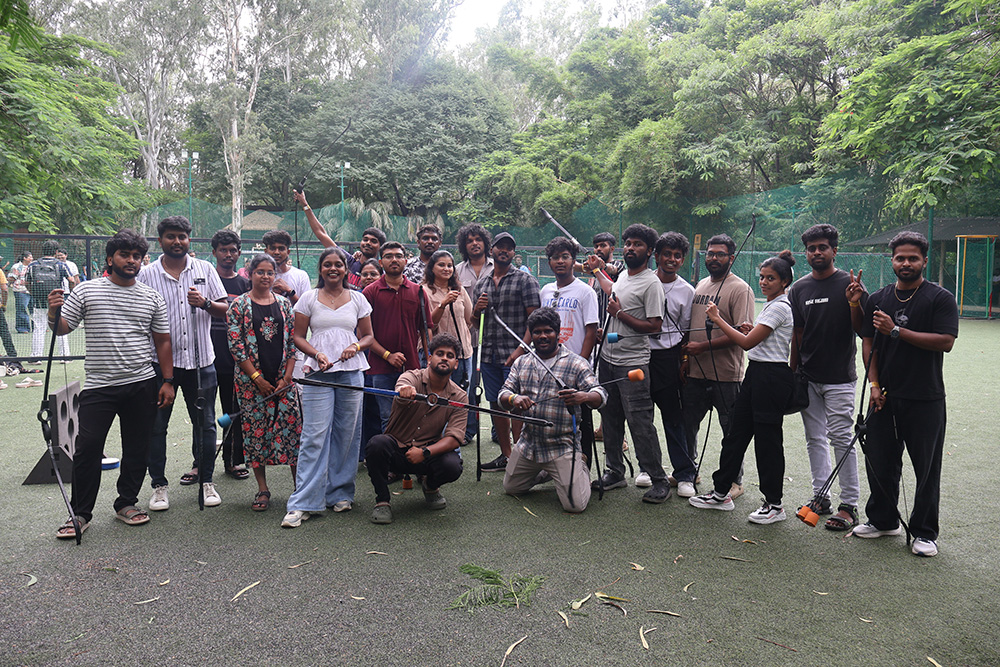 The team gathered on an outdoor archery range holding bows after a session